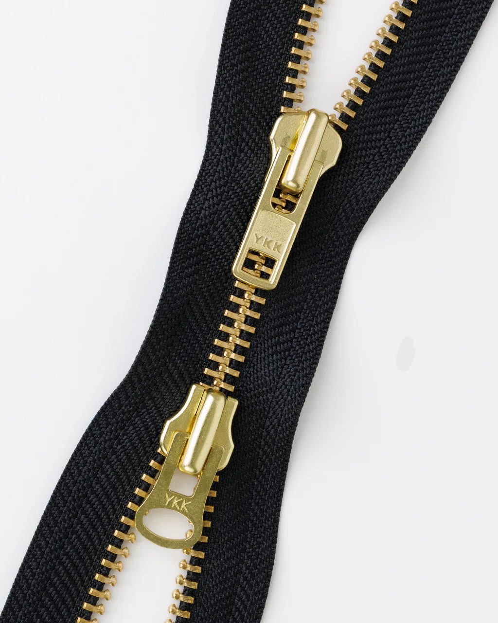 A two-way zipper with two brass sliders.